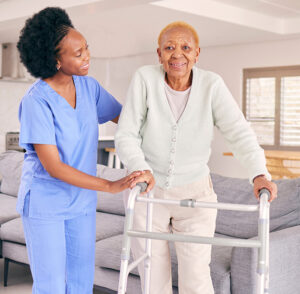 Nurse, elderly woman and walking frame for support.